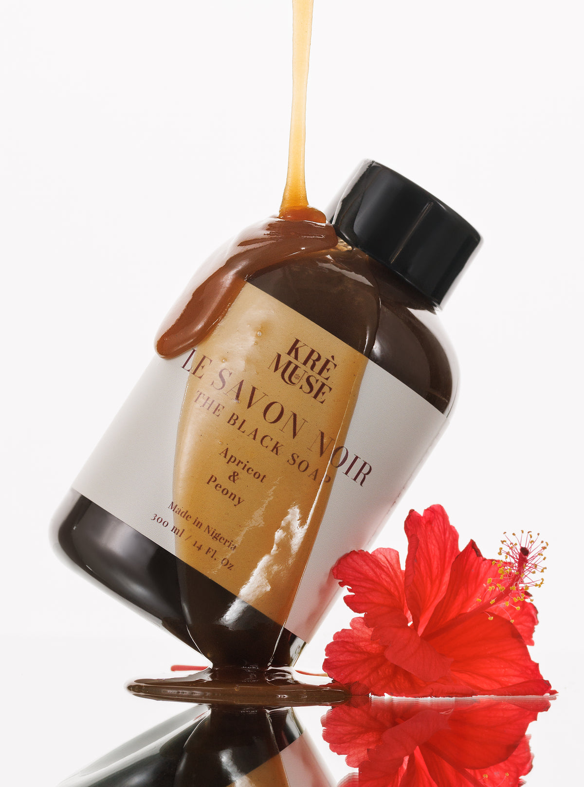 Bottle of Kèr Muse Le Savon Noir with a red flower on a white background